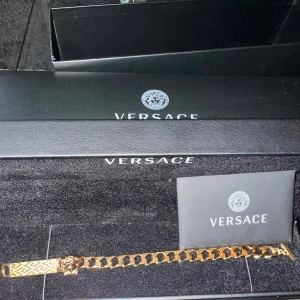 Guldarmband från Versace - Elegant guldarmband från Versace med ett ikoniskt Medusa-huvud och geometriskt mönster. Helt ny köpt på zalando för ca 1 år sedan men har ej använding av den då jag igentligen köpte den i present till nån annan, 24k guld kan gå ner i pris vid snabb affär 