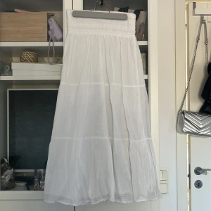 Vit långkjol från Gina Tricot - Säljer en vacker vit långkjol från Gina Tricot. Kjolen har en elastisk midja och ett luftigt fall som ger en skön och avslappnad känsla. Perfekt för varma dagar och kan enkelt matchas med olika toppar. 🌼kom privat för fler bilder☀️