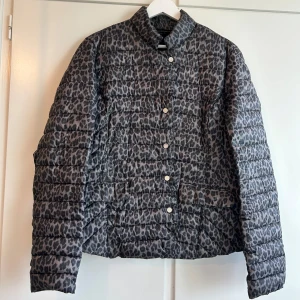 Grå leopardmönstrad pufferjacka - Snygg grå pufferjacka med leopardmönster och knappar framtill och fickor. Jackan har en quiltad design och långa ärmar, perfekt för våren! Skriv om du vill ha mer info eller fler bilder ✨