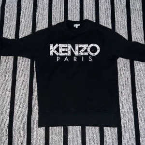 Svart sweatshirt från Kenzo - Snygg svart sweatshirt från Kenzo med stort logotryck på framsidan.Riktigt skön och snygg tröja,kan användas till alla tillfällen. Perfekt för en stilren look. pris går och diskutera vid snabb affär 