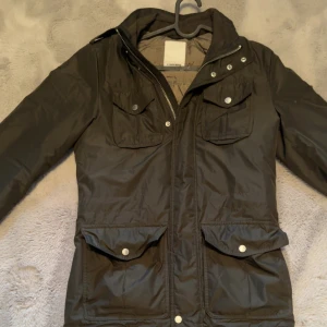 J.Lindberg jacka - Tja säljer nu denna snygga mörkgröna jacka från J.Lindberg med dragkedja och knappar framtill. Jackan har flera praktiska fickor.