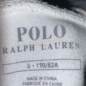 Vit hoodie från Ralph Lauren - Säljer en stilren vit hoodie från Ralph Lauren med dragkedja och det klassiska broderade logotypen i blått på bröstet. Perfekt för en avslappnad look.