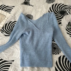 Ljusblå ribbad tröja - Säljer en superfin ljusblå ribbad tröja med v-ringning. Den är långärmad och har en tight passform som sitter snyggt på kroppen. Perfekt för både vår och höst när det är lite kyligare ute. Tröjan är i nyskick och redo för en ny ägare!
