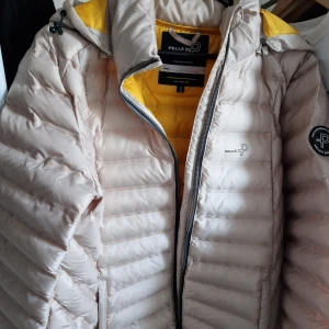 Pelle P Tempest stl XL - Denna vindtäta och värmande dunfria jacka är utvecklad för att fungera som ett perfekt alternativ mellan säsongerna då vädret varierar. Nypris 2300 kr, inköpt 2024 Färgen är beige, svårt att få till den på bild
