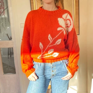 Stickad tröja med blomma - Häftig tröja som är varm. Har resor i slutet. Varm men inte stickig. Orange röd färg.