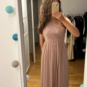 Klänning - Klänning perfekt till bal. Har aldrig använts, prislapp kvar. Jag är 180 den når nästan ner till marken, på bilderna är den inte knäppt. Köparen står för frakt. 