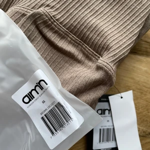 Bruna ribbade leggings från Aim'n - Snygga bruna ribbade leggings från Aim'n i storlek XS. Perfekta för en stilren och bekväm look. De har en hög midja och är tillverkade i ett stretchigt material som ger en tight passform.