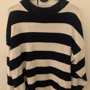 Randig tröja i bomull - ÄR MÖRKBLÅ, SER SVART UT PÅ BILD🩷Säljer en stilren randig tröja i 100% bomull. Tröjan har breda blåa och vita ränder och en ribbad krage. 