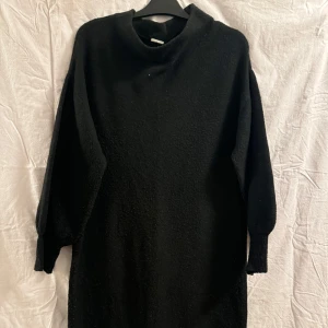 Svart stickad klänning - Snygg svart stickad klänning med lång ärm och enkel design. Perfekt för kyligare dagar med sin mysiga och bekväma passform. Har muddar längst ner på armarna den är lite knopprig  men är i bra skick 