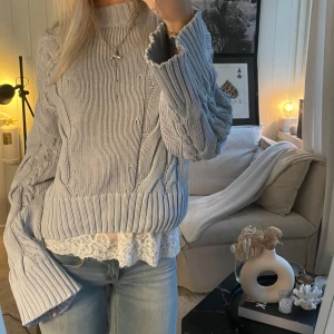 Ljusblå stickad tröja - Säljer en mysig ljusblå stickad tröja med kabelstickat mönster. Tröjan har långa ärmar och en avslappnad passform, stilren och lätt att matcha med olika outfits.