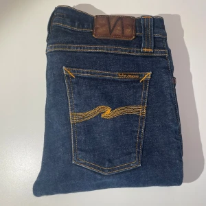 Mörkblå Nudie Jeans - Riktigt feta mörkblåa nudie jeans i modellen Tube Tom. Storlek 28/30. Oanvänt skick 10/10. Priset är inte hugget i sten, skriv vid minsta fråga eller fundering!