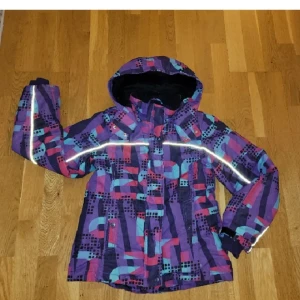 Färgglad vinterjacka från Lindex - Säljer en färgglad vinterjacka från Lindex med ett unikt mönster. Jackan har en huva och reflexdetaljer för extra synlighet. Perfekt för kalla dagar! Använd, men inga defekter. Tvättad!