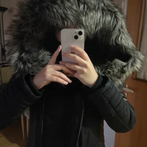 Svart parkajacka med päls från ONLY - Snygg svart parkajacka från ONLY med stor huva kantad av grå päls. Jackan har dragkedja och långa ärmar, perfekt för kyliga dagar.