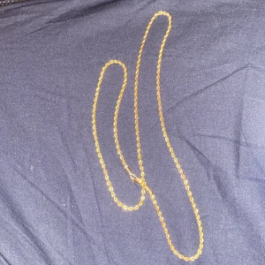 Guldhalsband 65-70cn - Elegant guldfärgat halsband med en tvinnad kedja. Perfekt för att lägga till en touch av stil till din outfit. Kedjan har en säker låsning som håller den på plats.