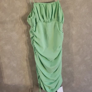 Grön klänning från Glamorous Care - Snygg grön klänning köpt på Nelly med rynkade detaljer och smala axelband. Perfekt för en somrig look. Oanvänd med lapparna kvar