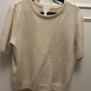 Beige tröja från H&M - Säljer en stilren beige tröja från H&M. Tröjan har korta ärmar och en rund halsringning
