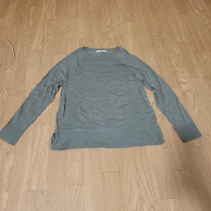 Grå tröja från Ellos - Säljer en stilren grå/grön tröja från Ellos. Tröjan har långa ärmar och en rund halsringning. Perfekt för en avslappnad look.