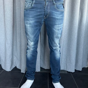 Blå jeans från Replay - Snygga blå jeans från Replay med en klassisk slitna detaljer. De är i modellen Anbass, vilket är en modern och bekväm passform. Perfekta för en avslappnad stil.