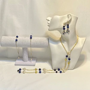 Blått och guldigt smyckeset med pärlor - Elegant smyckeset med halsband och örhängen i blått och guld. Halsbandet har dekorativa pärlor och blommotiv, medan örhängena är formade som blommor med blå detaljer. Perfekt för att ge en färgklick till din outfit.Ett par örhängen och ett par armband plus en halsband handgjorda mycket mycket fint nytt oanvänd 