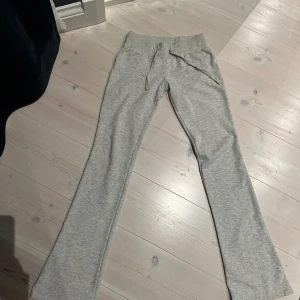 Grå low waist mjukisbyxor Nelly - Snygga och sköna low waist mjukisbyxor från Nelly i storlek XXS🎀Sitter bra över midja på mig som vanligtvis är XS/32, men alldeles för långa i benen därav säljer jag dem. Endast testade, på sista bilden ser man hur mycket extra tyg på mig som är ca 150cm!🤗