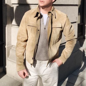 Beige mockajacka Tiger of Sweden  - Väl omhändertagen jacka från Tiger of Sweden gjord i beige goat suede. Den är kort i modellen med en bred krage. Har två bröstfickor samt två innerfickor. Den stängs med stora knappar. Det finns några små fläckar på jackan vilket syns på bilderna. 