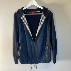Burberry Cardigan - Riktigt schysst Burberry cardigan med Burberry mönstret på insidan och goa detaljer som Burberry märket på jacken och ”BURBERRY” ingraverat i zippern. Size48/S-M Den är i bra skick bortsätt från ett litet hål i fickan. Priset är ej hugget i sten.