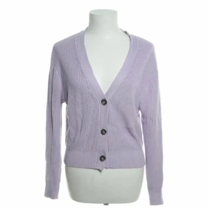 Ljuslila kofta med knappar - Säljer en superfin ljuslila kofta med stora knappar framtill. Den är stickad och har en v-ringad design som gör den perfekt för både vardag och lite finare tillfällen. Koftan har långa ärmar och en skön passform. Perfekt för vår och höst!