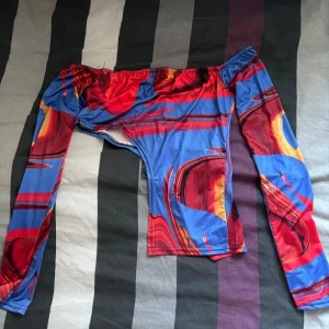 Blå och röd mönstrad topp från PrettyLittleThing - Säljer en  blå och röd mönstrad topp från PrettyLittleThing. Den har långa ärmar och en tight passform, perfekt för en utekväll eller fest. Materialet är stretchigt och bekvämt, vilket gör den både snygg och skön att bära.