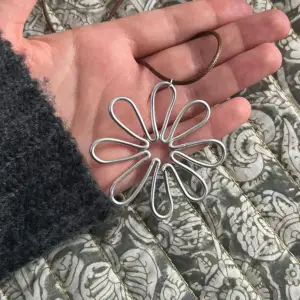 Egengjort halsband med berlock silvrig blomma gjort i aluminiumtråd, med brunt läderband/snöre, justerbart! Skriv för frågor och skicka prisförslag <3