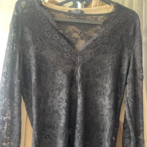 Svart spetsblus från Shein - Säljer en elegant svart spetsblus från Shein i storlek XS. Blusen har en v-ringad design och långa ärmar, perfekt för en festlig kväll. Den är gjord i ett vackert spetsmaterial som ger en lyxig känsla.