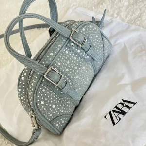 Zara väska - väska från Zara blå med rhinestones. Bandet har gått av så det är ett hål på ena sidan (se bild) och de är lite slitet på handtagen