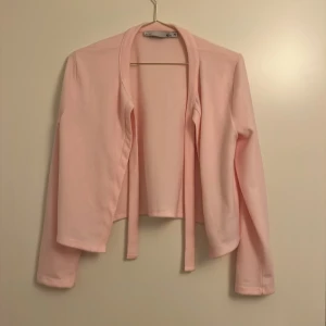 Rosa kofta från 157🥂 - Säljer en söt rosa korta från 157 i storlek XS. Koftan har långa ärmar och ett knytband framtill för en stilren look. Perfekt för vår och sommar!!!🥂