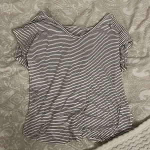 Randig t-shirt från Lindex - Säljer en randig t-shirt från Lindex i svart och vitt. Den har en v-ringad hals och korta ärmar. Väldigt tunt material.