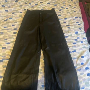 Svarta byxor i syntetmaterial - Snygga svarta byxor i syntetmaterial med hög midja och en loose passform från Vero Moda. Storlek EU 32. Säljer pga rensning i garderoben💕