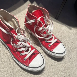 Röda Converse All Star sneakers - Säljer ett par klassiska röda Converse All Star sneakers i textil med vita snören och detaljer. Skorna har en hög modell med den ikoniska loggan på sidan. Använda fåtal gånger, mycket fint skick❣️❣️