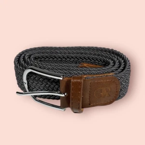 Grått bälte från or èlan - Grått flätat bälte med bruna läderdetaljer från Or Èlan UF, bältet är strechigt och passar därmed alla😊