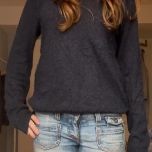 Stickad tröja - Säljer en stilren mörkblå tröja med långärmad design. Perfekt för kyligare dagar och enkel att matcha med jeans eller andra byxor.