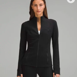 Svart träningsjacka från Lululemon - Helt my med prislapp på i storlek 4 (EU 32) Snygg och funktionell svart träningsjacka från Lululemon. Pris kan diskuteras. Jackan har en dragkedja framtill och långa ärmar med tumhål. Perfekt för träning och vardagliga aktiviteter. Den är tillverkad i ett stretchigt material som ger en tight passform.