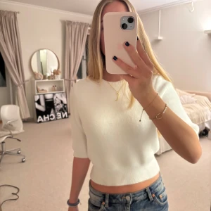 Vit croppad tröja - Säljer en stilren vit croppad tröja med korta ärmar. Perfekt för en avslappnad look. Tröjan är enkel och passar till det mesta. Perfekt för dig som gillar en minimalistisk stil.