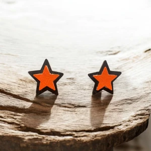 Stjärnformade örhängen i orange och svart (clips) - Snygga stjärnformade örhängen i trä, med en iögonfallande design i orange och svart. Perfekta för att ge en färgklick till din outfit. Örhängena har en clip-on funktion vilket gör dem enkla att använda utan hål i öronen.