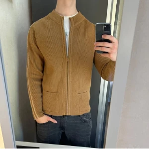 Beige cardigan - Beige cardigan i nästan nyskick, utan lapp. Storlek M och perfekt passform på modellen (187 cm, 80 kg), som visar den stiliga och eleganta looken. Denna cardigan ger en sofistikerad känsla och passar både till vardags och fest. Med vänlig hälsning, DLVClothing_sth  