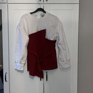 Vit och röd blus från Shein - Trendig blus från Shein i vitt och rött med långärmad design. Blusen har en unik knytning framtill som ger en snygg detalj. Perfekt för att ge din outfit en färgklick!