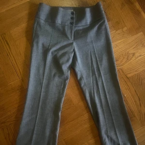 Grå kostymbyxor - Snygga grå kostymbyxor med hög midja och knappar framtill. Perfekta för en stilren look.