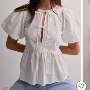 Vit blus med puffärmar och knytning - Säljer en söt vit blus från nelly med puffiga kortärmar och knytning framtill. Helt ny. Blusen har en luftig passform och en feminin touch med sin knytning och volangdetaljer.