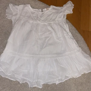 Vit längre  blus med volangdetaljer - En längre blus från Gina Young , den här två tunna lager och passar när det är en varm sommardag ute men även på fester och till vardags looken. Den här knapp där bak men snöret man fäster knappen i har åkt av men går att fixa eller så tar man en sån nål som sitter säkert och bra.