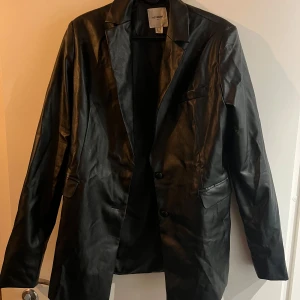 Svart kavaj  - Svart kavaj i skinnimitation från Extro & Vert. Aldrig blivit använd. Den är knövlig då den legat i en flyttkartong. 