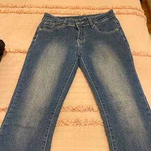 Blå jeans med broderade bakfickor -  blå jeans med broderade detaljer på bakfickorna. De har en bekväm passform. De är ganska så sköna och den är lågmidjade och de är stora i formen så de är inte så tajta. Men knappen har gått av. Annars är de helt nya.
