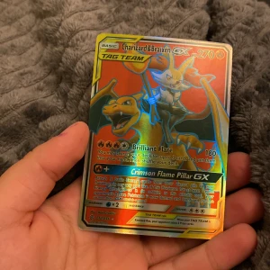 Charizard & Braixen GX Pokémon-kort - Säljer ett Charizard & Braixen GX TAG TEAM Pokémon-kort med 270 HP. Kortet har en holografisk yta och innehåller attacker som Brilliant Flare och Crimson Flame Pillar GX. Perfekt för samlare eller spelare som vill stärka sin kortlek.