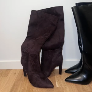 Bruna mockastövlar med spetsig tå - Snygga bruna stövlar i mocka med spetsig tå och hög klack. Perfekta för höst och vinter, dessa stövlar ger en elegant touch till din outfit.  OBS! Aldrig använda 