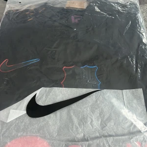 Svart tröja från Nike - Säljer en svart tröja från Nike med färgglada detaljer. Perfekt för sportiga tillfällen eller som en stilren vardagströja. Tröjan är ny och kommer i originalförpackning.